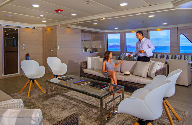 A woman served a drink sitting on the couch in the lounge